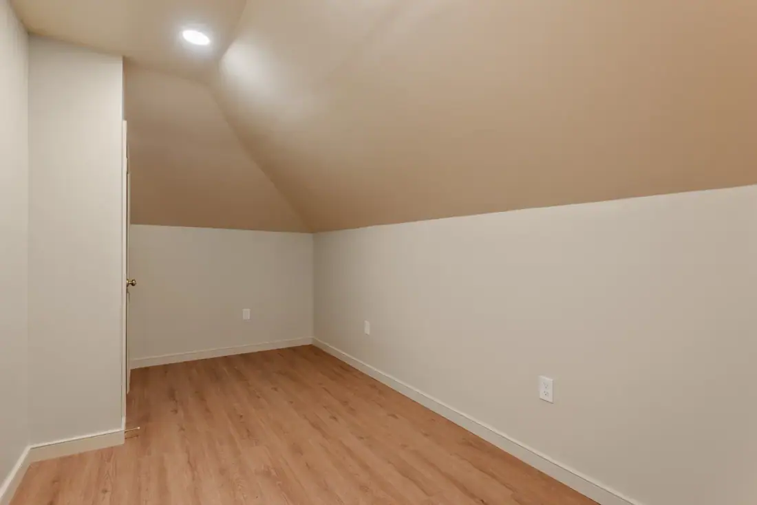 Converted attic room with knee walls and wood look plank flooring