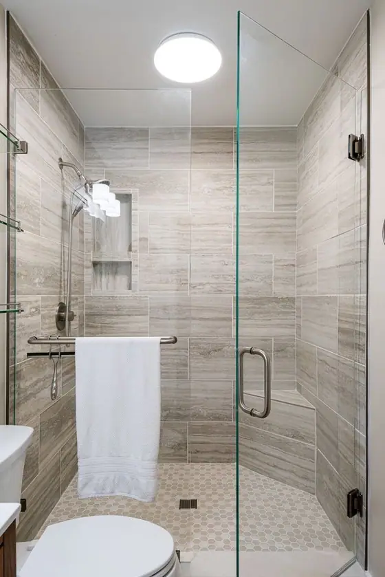 Frameless glass shower with gray plank tile walls and a hex tile floor