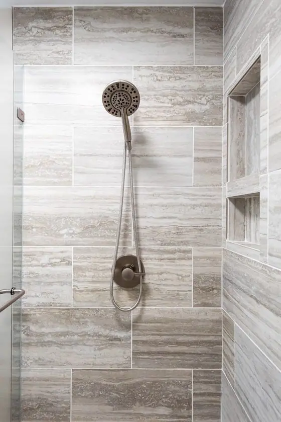 Gray plank tile shower wall with a handheld shower head and niche
