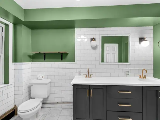 Bathroom with a green painted niche, white subway tile and a dark double vanity