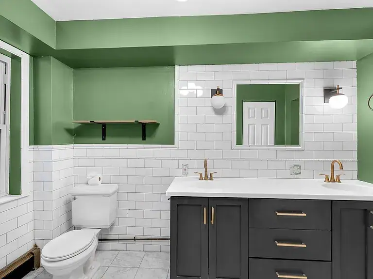 Bathroom with a green painted niche, white subway tile and a dark double vanity