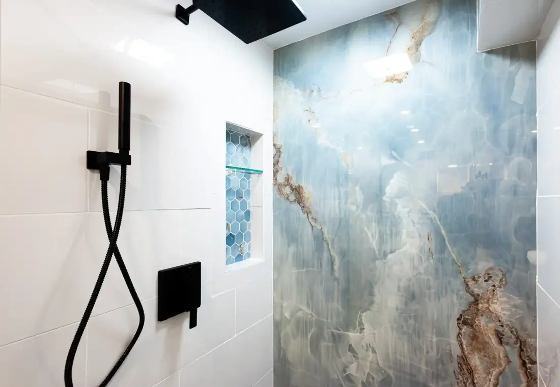 Shower wall in large format blue and gold marble look slab with matte black fixtures