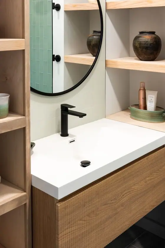 Matte black faucet on a white integrated sink with wood shelves alongside