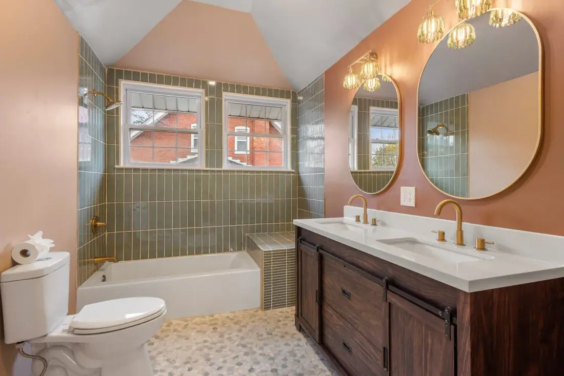 Green tile tub surround, pill shaped mirrors and a dark wood double vanity