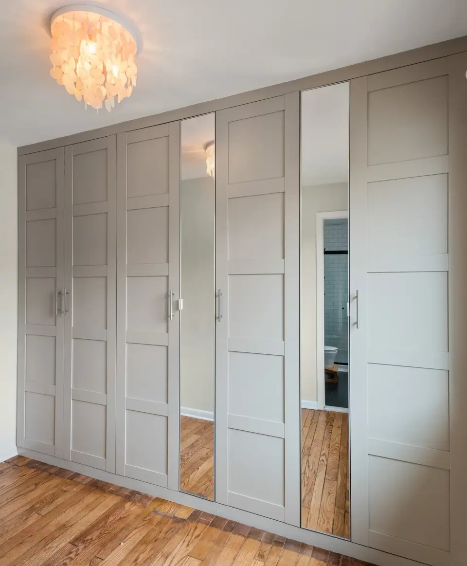 Wall of built in wardrobe cabinets with shaker doors and mirrored panels