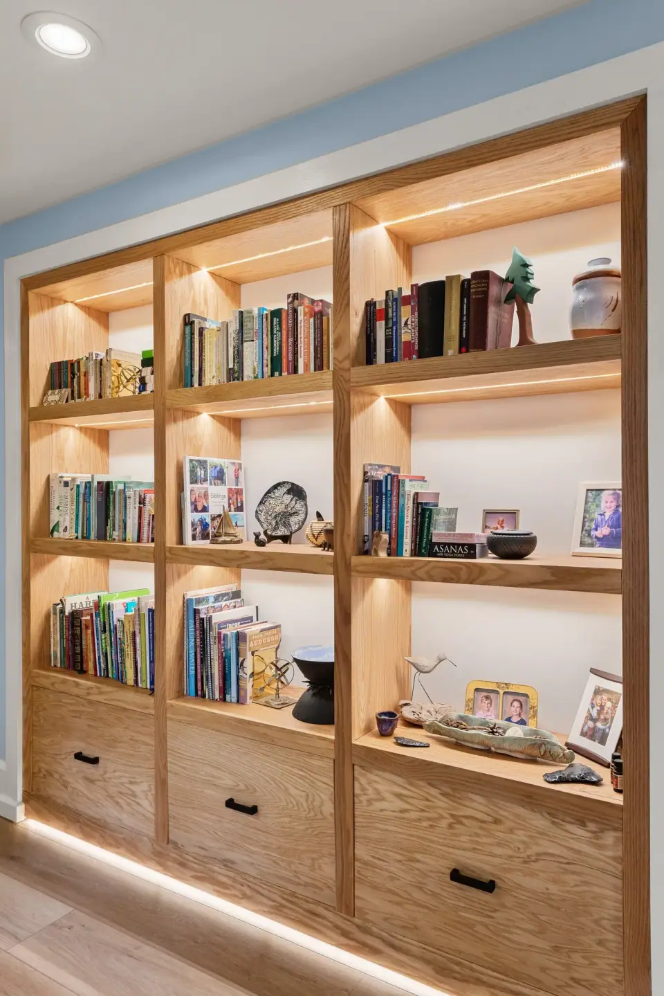 Floor to ceiling built in bookshelves lit from within, with a glowing toe kick