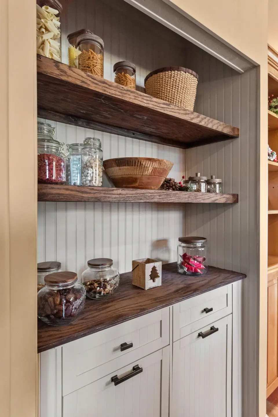 Pantry nook with open wood shelves above white base cabinets