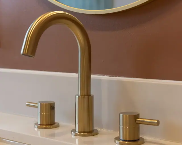 Brushed brass faucet on a white vanity top