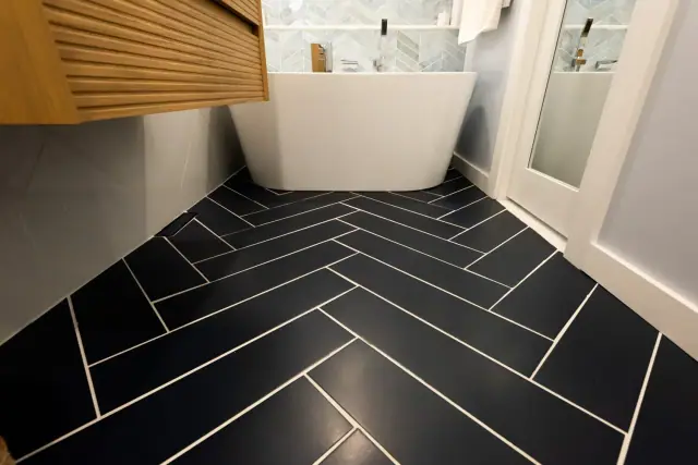 Black herringbone floor tile running up to a freestanding tub