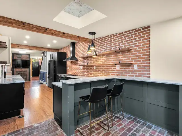 Kitchen bar with dark green cabinets, brick wall and a skylight above