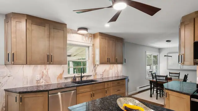 Kitchen remodel with maple shaker cabinets, dark granite island and a marble look tile backsplash