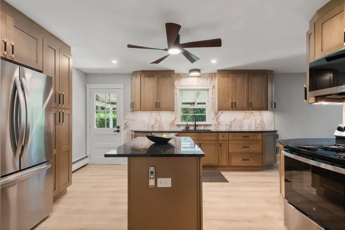 Remodeled kitchen with stainless refrigerator, granite island and wood look flooring