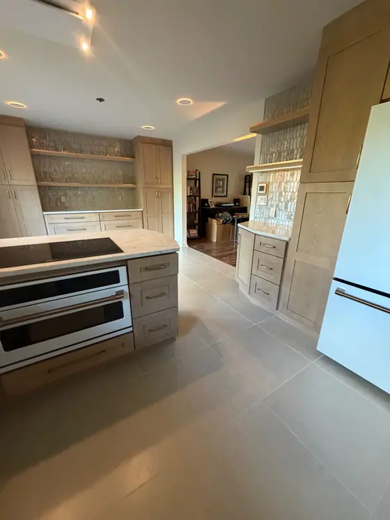Kitchen peninsula with wall ovens and tall light wood pantry cabinets