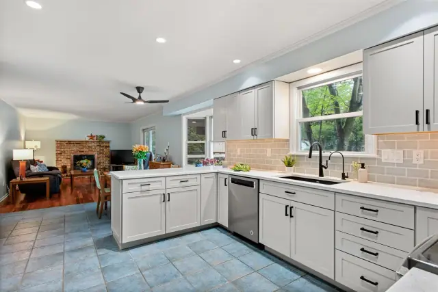 Bright L-shaped kitchen with white shaker cabinets, subway tile backsplash and a view into the living room