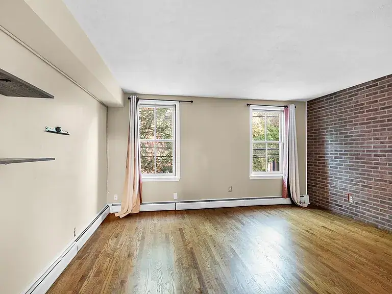 Renovated room with an exposed brick wall, hardwood floors and tall windows