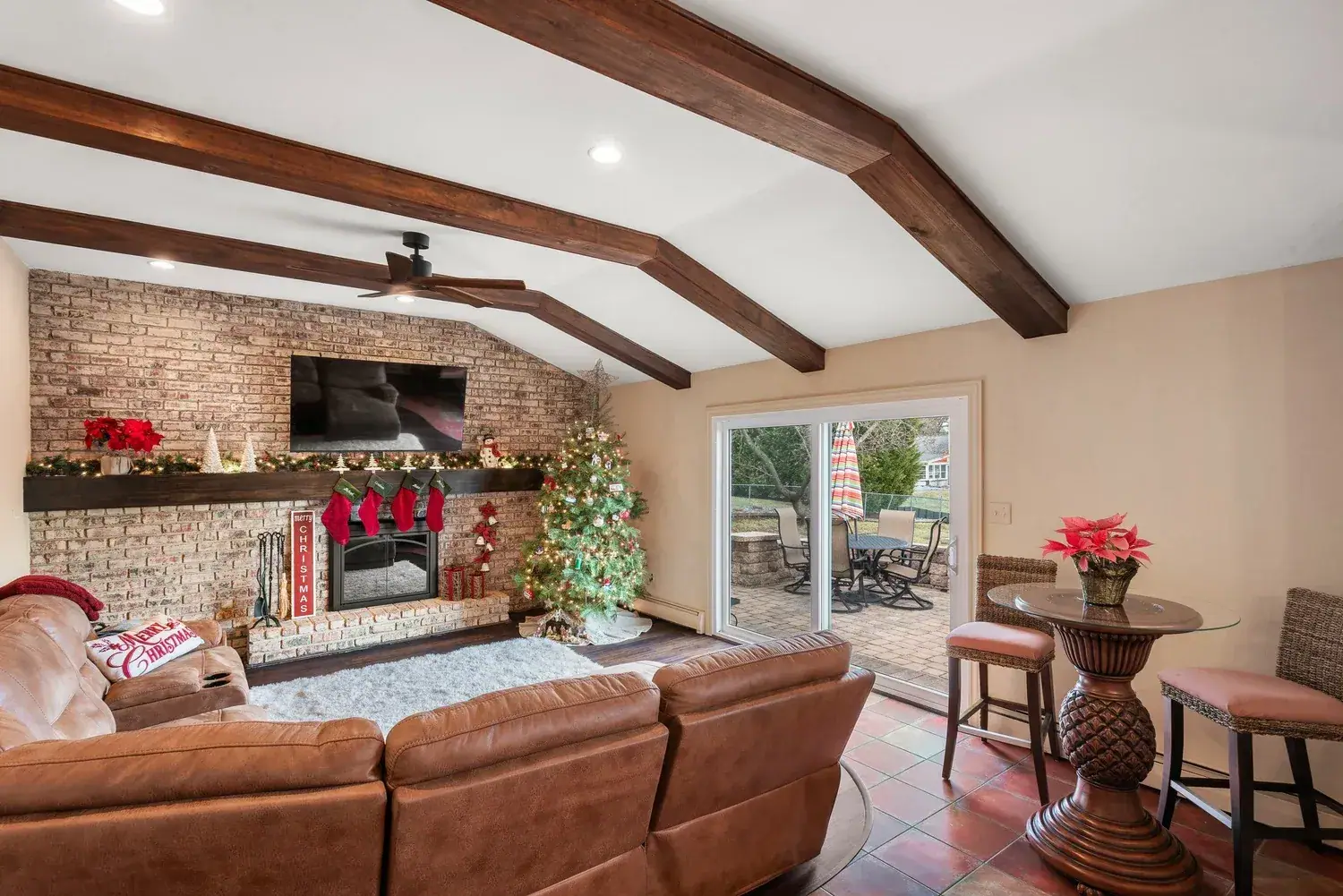 Living room with wood ceiling beams, a brick fireplace wall and sliding doors to the yard