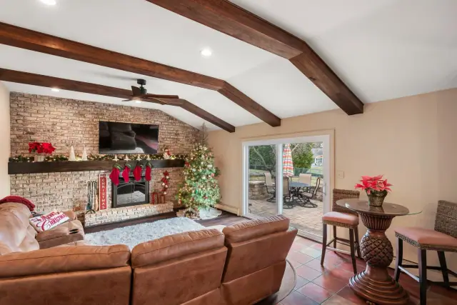 Living room with wood ceiling beams, a brick fireplace wall and sliding doors to the yard