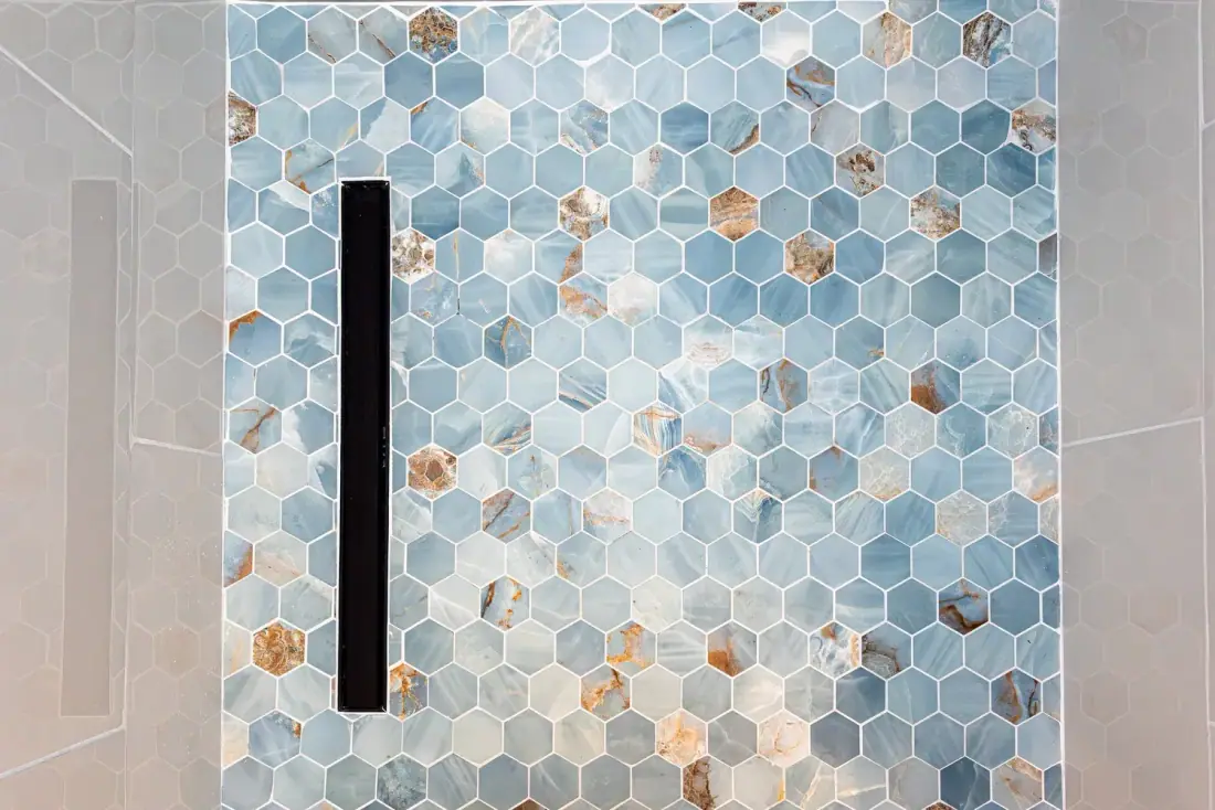 Blue and bronze hexagon mosaic shower wall with a slim black grab bar