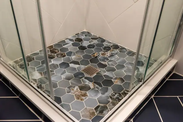 Hexagon stone mosaic shower floor inside a glass enclosure