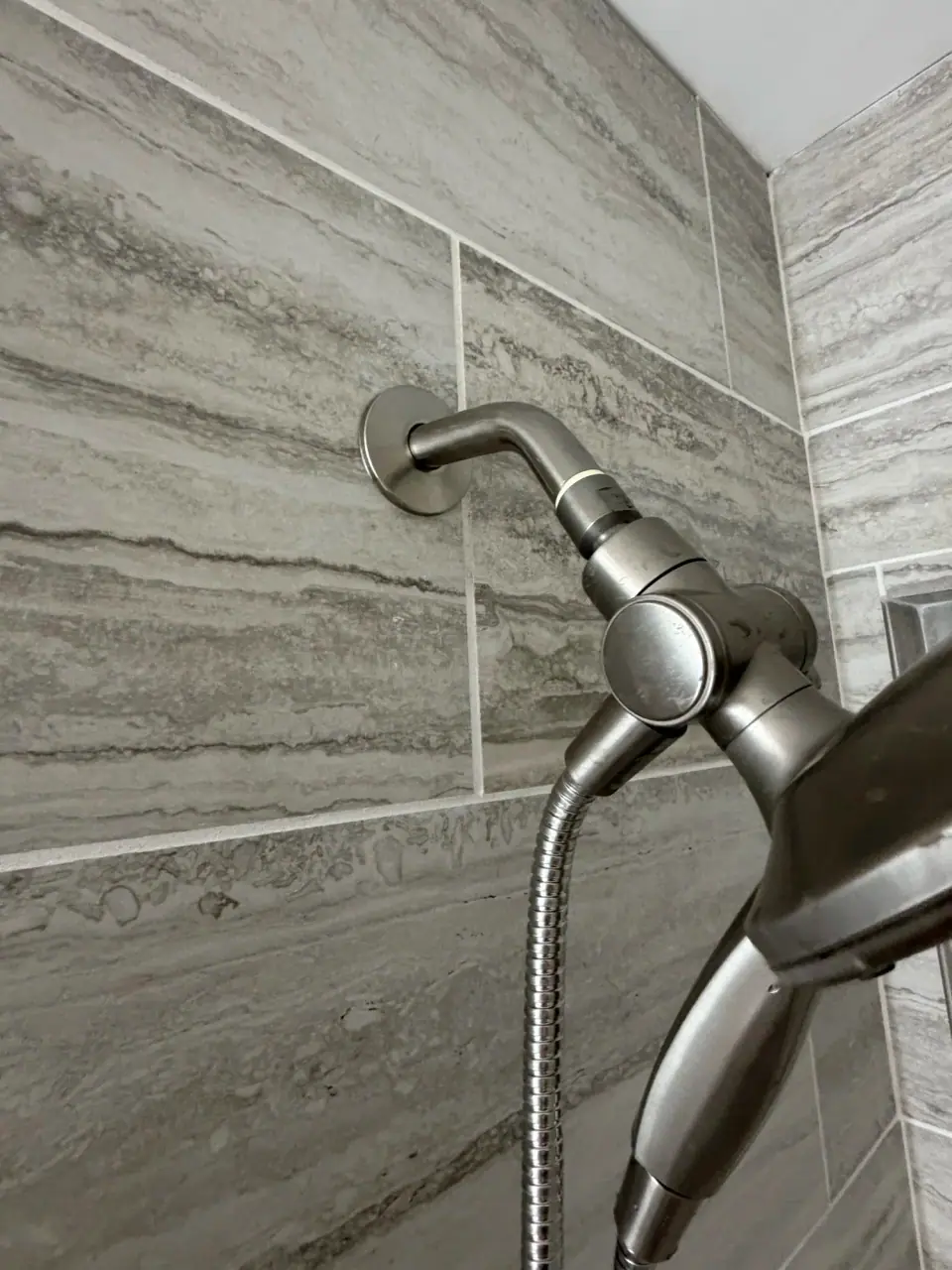 Gray plank tile shower wall with a brushed nickel handheld shower
